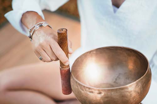 Woman sits on floor with sound bowl