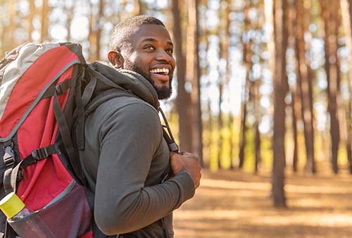 Man with backbacks gets ready to walk in the woods