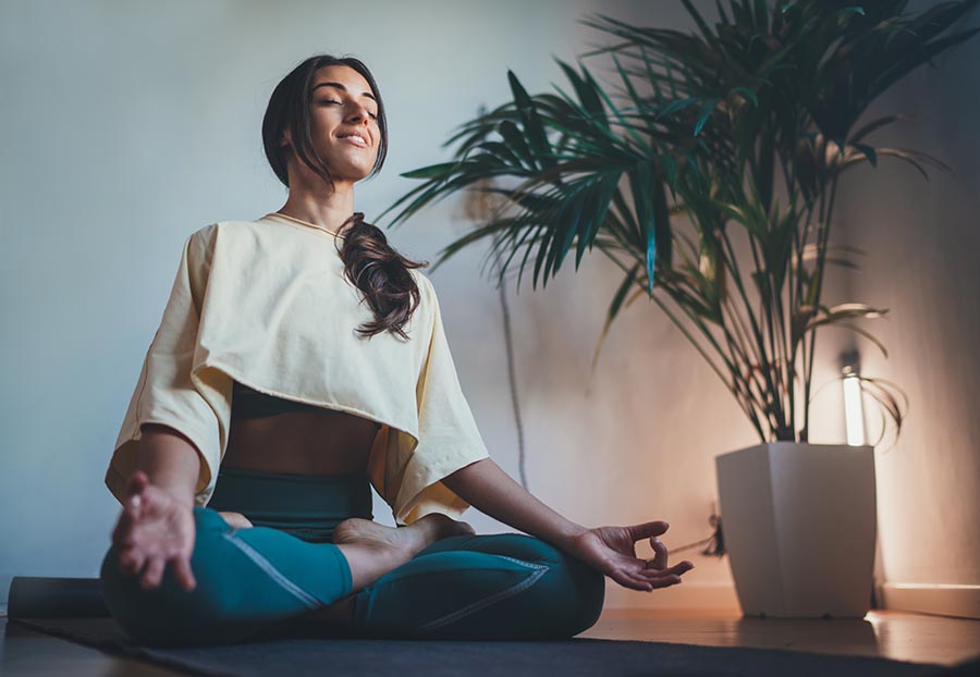 Woman sits on yoga mat and meditates