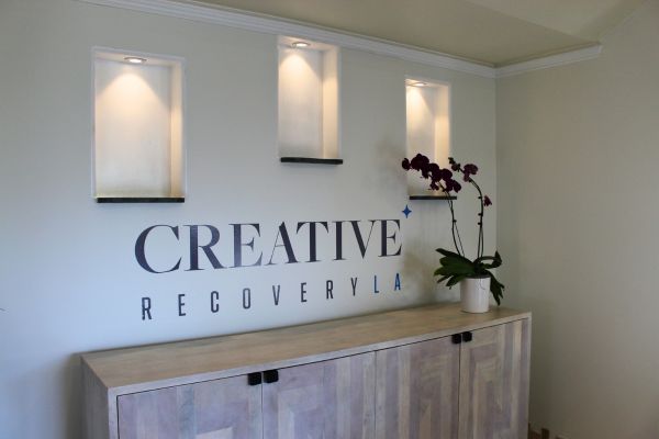 Creative Recovery LA logo displayed above a cabinet with a potted orchid