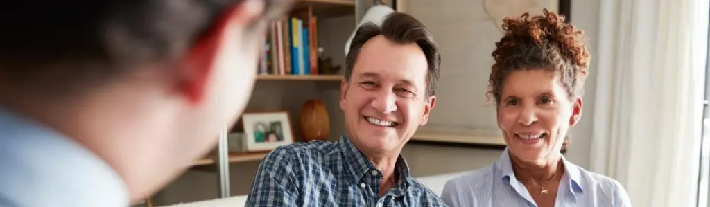 Two people smiling during a conversation in a room with bookshelves in the background.